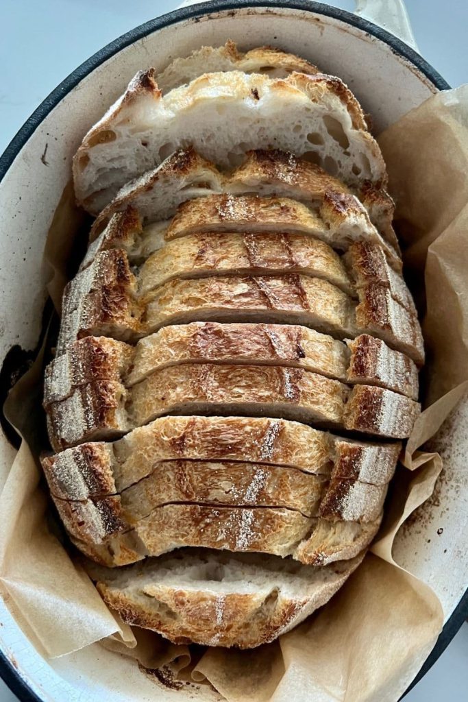 Sourdough batard that has been sliced and then placed back into a cream enamel Dutch Oven.