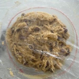 Sourdough Chocolate Chip Cookie dough covered with a plastic cover and refrigerated.