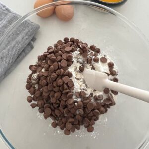 Dry ingredients in a glass bowl with the chocolate chips placed on top.