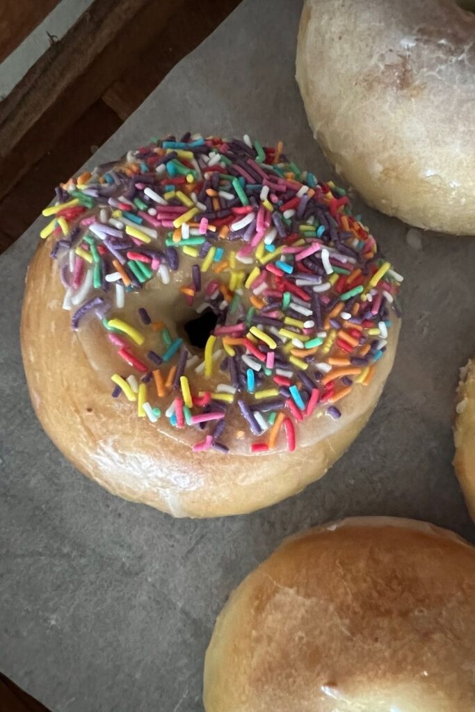 Baked sourdough donut topped with glaze and sprinkles