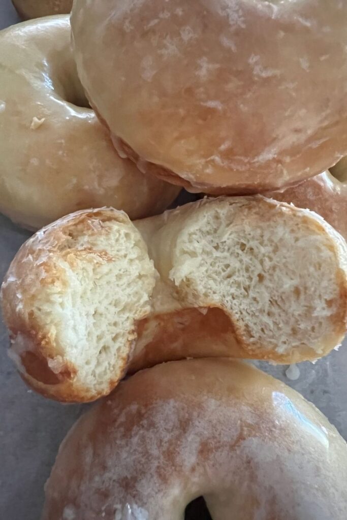 Close up image of baked sourdough donut with a bite taken out to show the texture of the crumb.