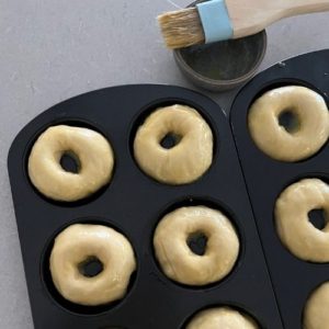 Brushing shaped donuts with melted butter.