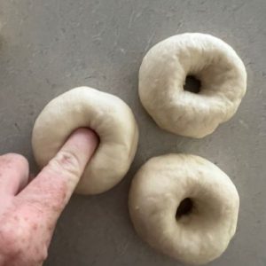 Poking holes in sourdough bagels to get the shape.