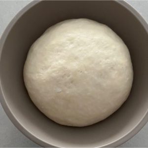 Soft sourdough pretzel dough risen after fermenting in a plastic bowl