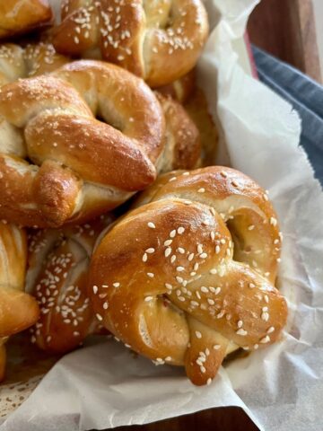 Soft Sourdough Pretzel Recipe - pretzels sitting in a wooden tray on top of a blue dish cloth