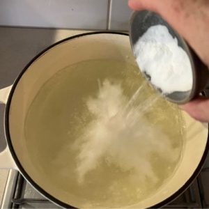 Adding baking soda to pot of boiling water