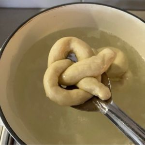 Removing pretzels from boiling water with slotted spoon