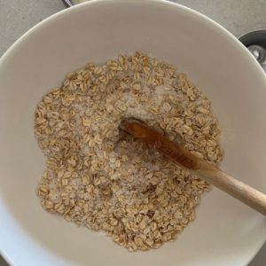 Sourdough Anzac Biscuits dry ingredients mixed together in a bowl with a wooden spoon.