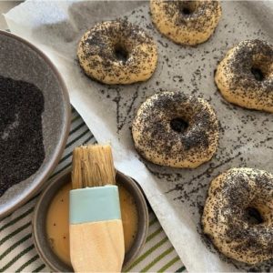 Applying egg wash and poppy seeds to sourdough egg bagels