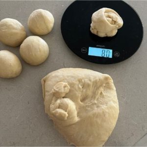 weighing individual pieces of egg bagel dough into 80g