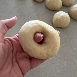 Shaping sourdough egg bagels by poking a hole in each ball of dough.