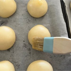 applying egg wash to sourdough brioche buns