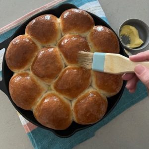 Brush the baked sourdough discard rolls with melted butter