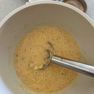 Bowl of foamy banana mixture with a Danish Whisk