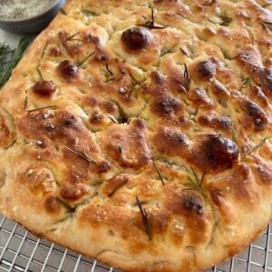 Golden brown focaccia bread cooling on a wire rack.