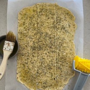 Use a cracker roller to perforate the sourdough vegan crackers.