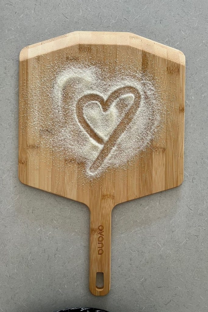 Pizza peel with semolina flour - a heart has been drawn in the semolina flour.