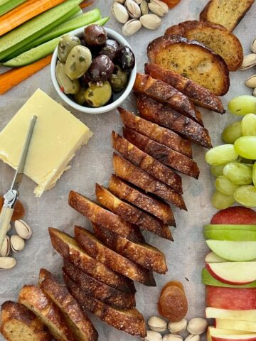 Sourdough crostini are the hero of this cheese platter featuring fresh fruit and vegetables, green tomato relish and dried fruits and nuts.