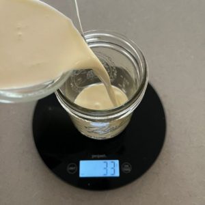 Pouring heavy whipping cream into a mason jar sitting on a scale