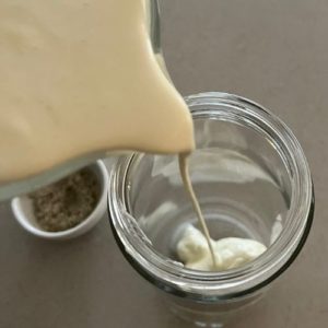 pouring heavy cream over natural yoghurt to make cultured cream
