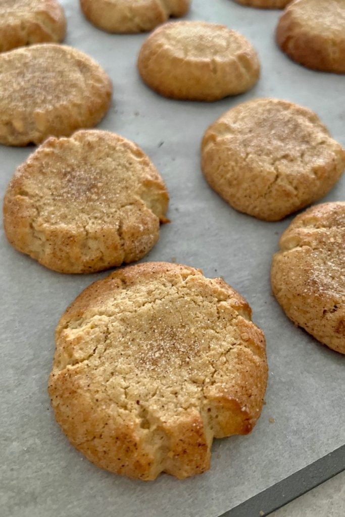Tray of freshly baked snickerdoodle cookies with crispier edges.