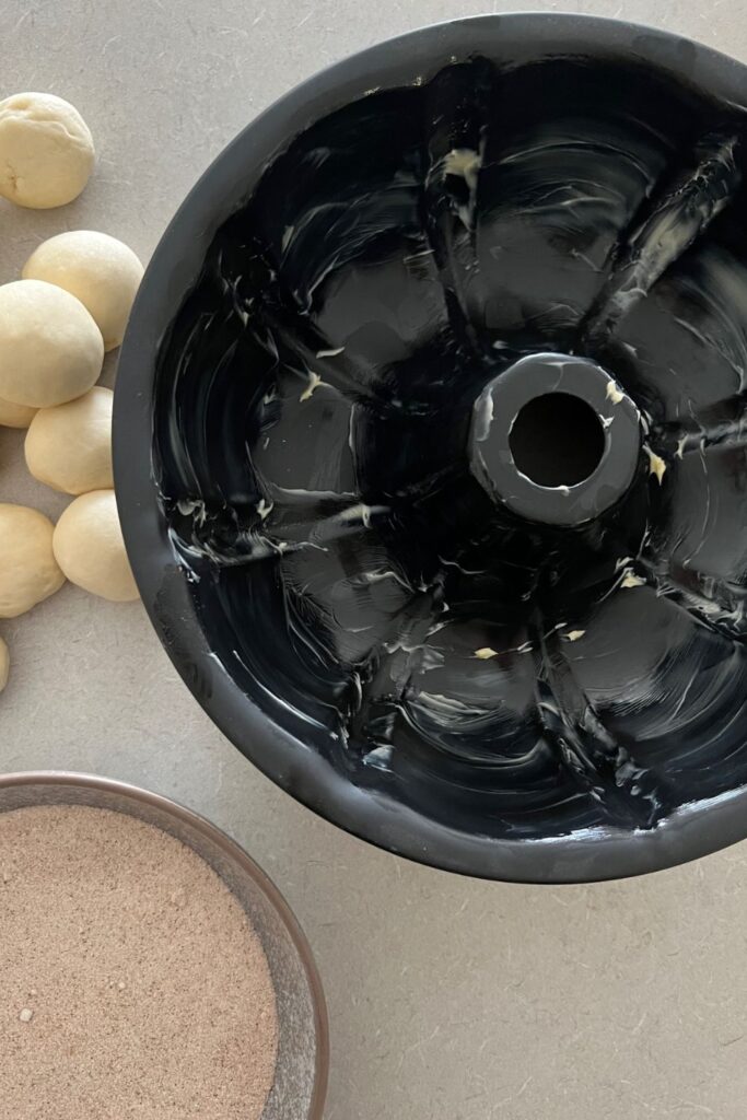 showing bundt pan liberally spread with butter to stop sourdough discard monkey bread from sticking.