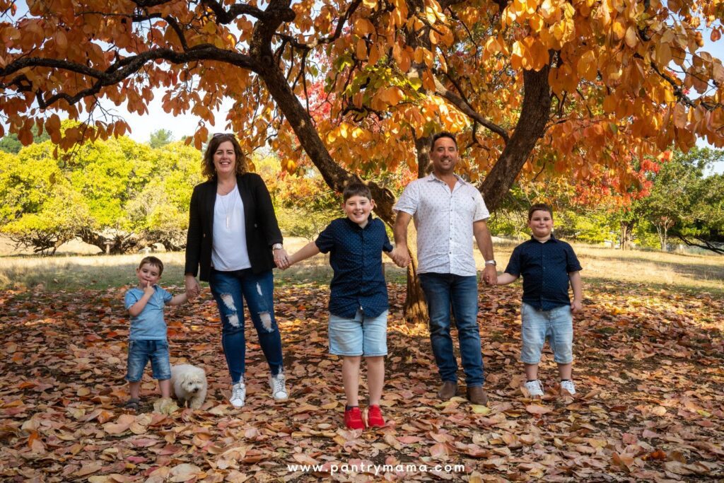 Kate from the Pantry Mama shares her sourdough secrets for busy moms. This photo shows Kate with her 3 children, husband and dog, standing under an autumn tree.