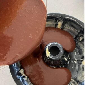 Pouring sourdough chocolate cake batter into the greased bundt tin.