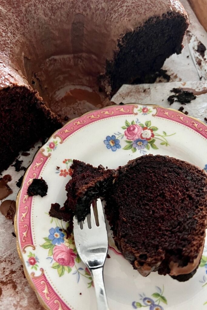 Long fermented sourdough chocolate cake cut up and placed on a floral plate. There is a fork with a piece of chocolate cake on it.