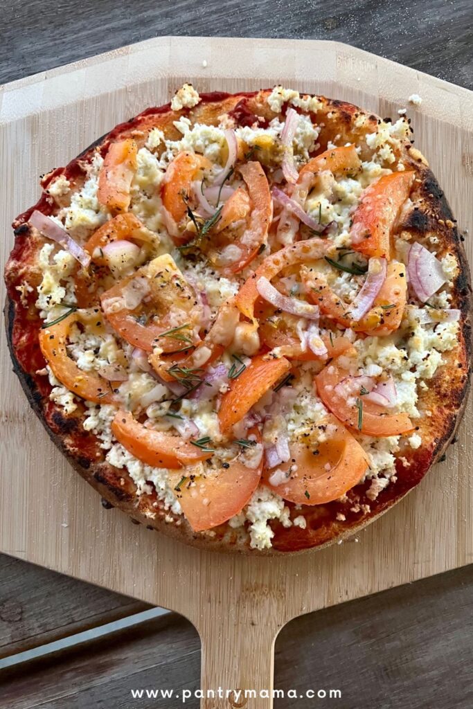 Homemade pizza topped with ricotta, fresh tomato, red onion