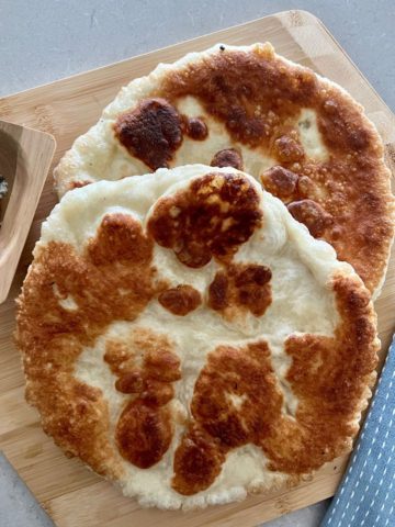 2 pieces of fried sourdough pizza sitting on a pizza peel with a light blue teatowel to the right.
