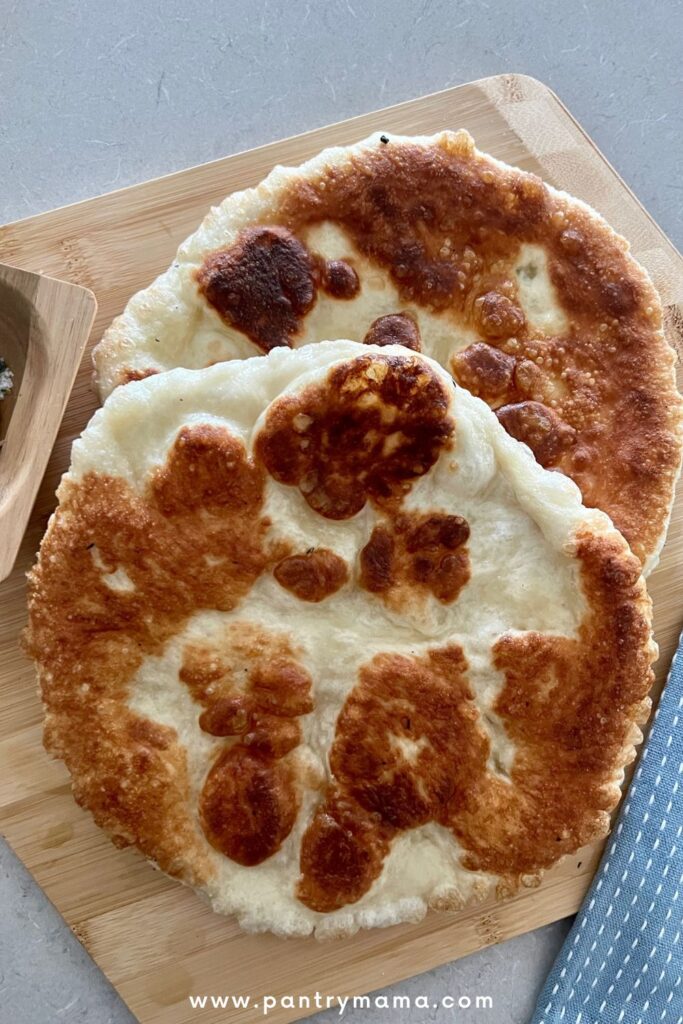 2 rounds of fried sourdough pizza dough sitting on a wooden board