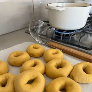 Sourdough pumpkin bagels sitting on the counter top next to a Dutch Oven on the stove. The water is being heated ready to boil the bagels.
