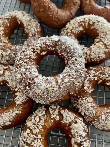 A pile of sourdough rye bagels topped with ground oats.