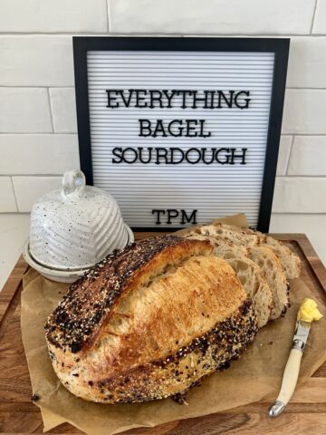 Sourdough Bread with Everything Bagel Seasoning sitting on a wooden board with an ivory knife ready to spread the bread with butter.