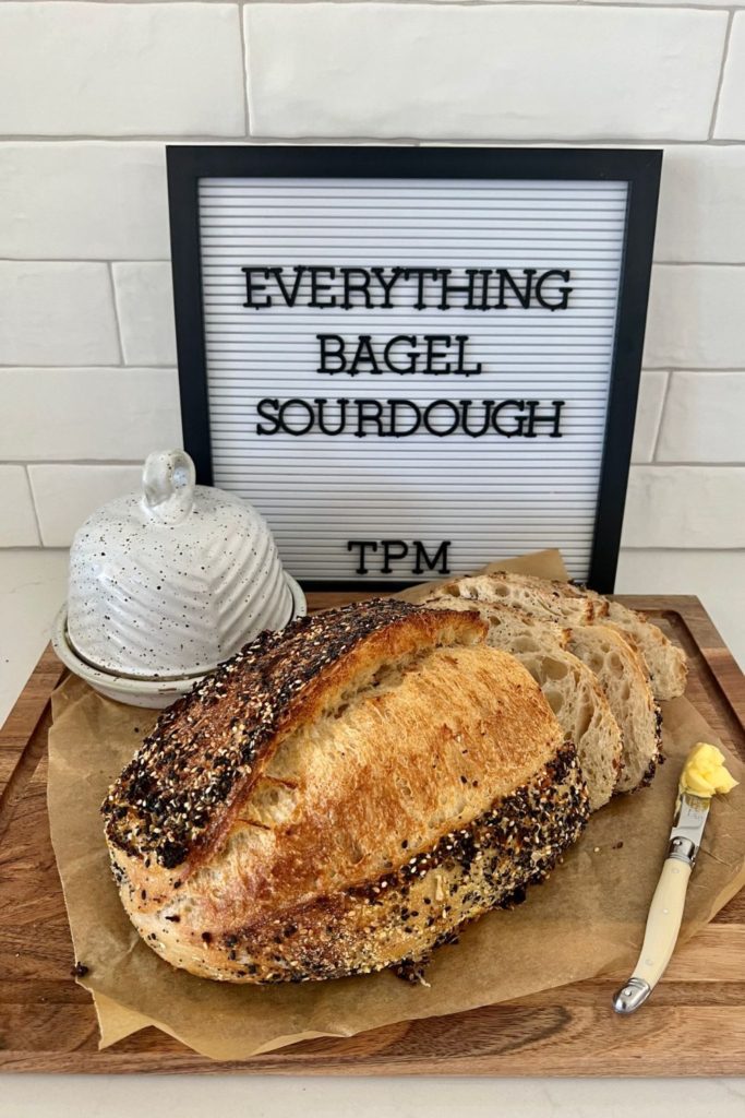 Sourdough Bread with Everything Bagel Seasoning sitting on a wooden board with an ivory knife ready to spread the bread with butter.