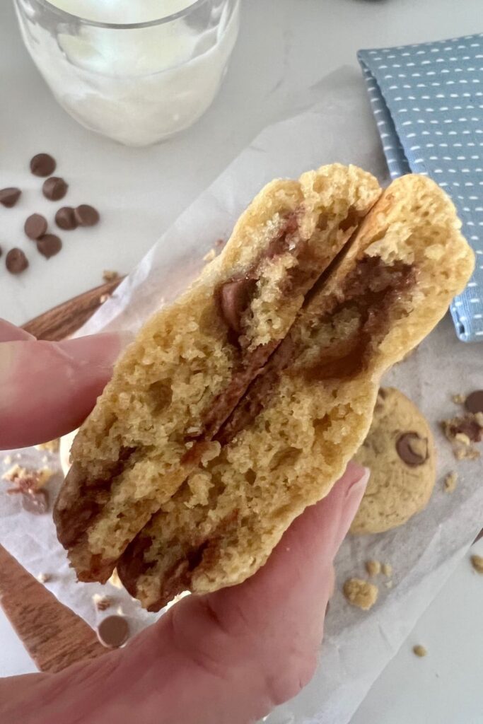 Photo of a sourdough chocolate chip cookie broken in half to show the soft and chewy texture.