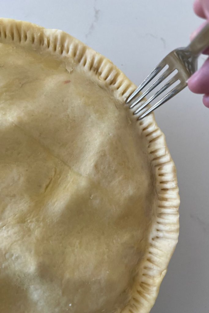 Crimping the edges of a sourdough pie crust with a fork.