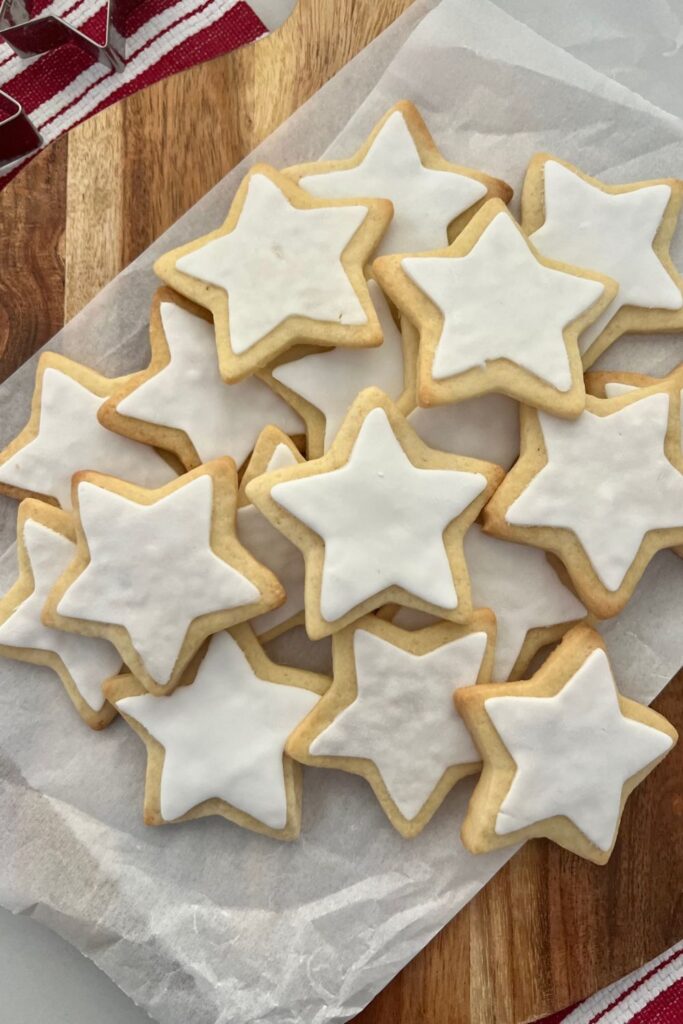 Sourdough Sugar Cookies in the shape of stars with white fondant on them. There is a red and white dish towel in the background.