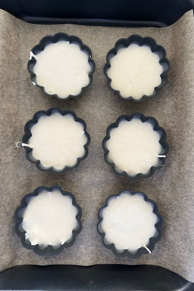 Six portions of sourdough starter sitting in silicone tart cases ready for the freezer.