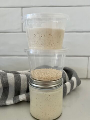 A small mason jar sitting on the counter. There are two small take out containers sitting on top of the mason jar.