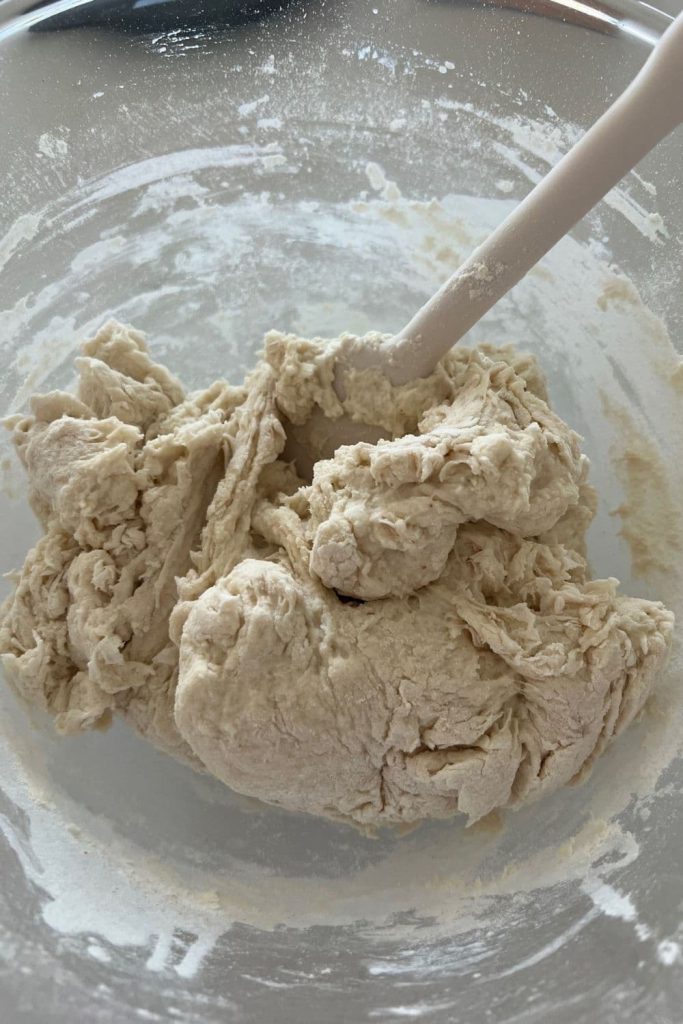 Shaggy dough mixed together using a white jar spatula.