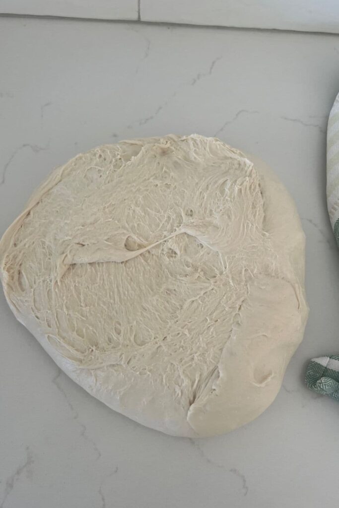 sourdough that has been flipped onto the counter from the bowl with the sticky side facing upwards.