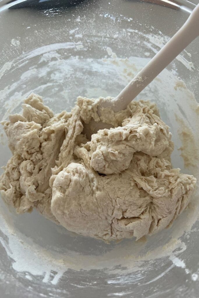 Shaggy dough that has just been mixed together using a white silicon spatula.