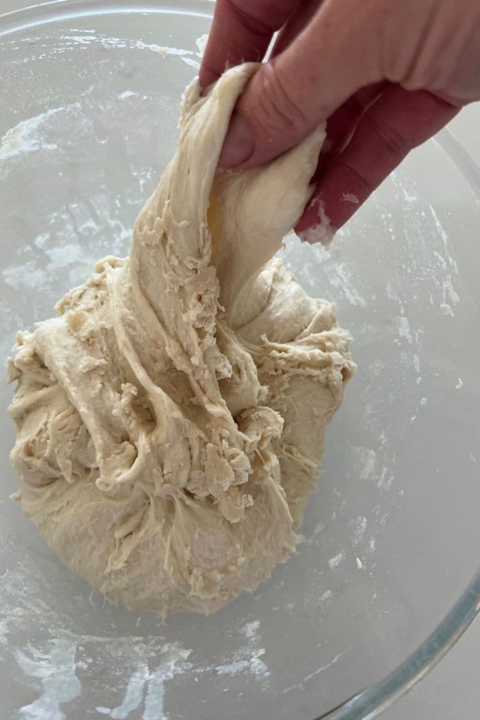 Sourdough dough that has been through autolyse and is now being pulled together to form a loose ball.