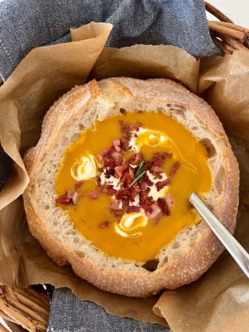 Sourdough Bread Bowl filled with pumpkin soup that has been topped with sour cream and bacon.