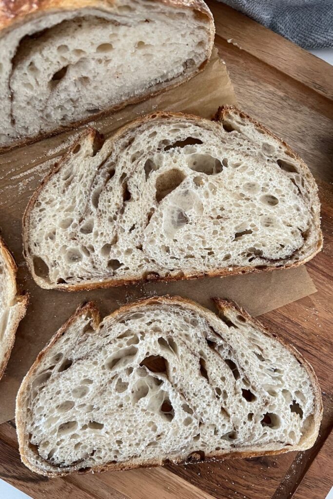 2 slices of Cinnamon Swirl Sourdough Bread sitting on a wooden board. 