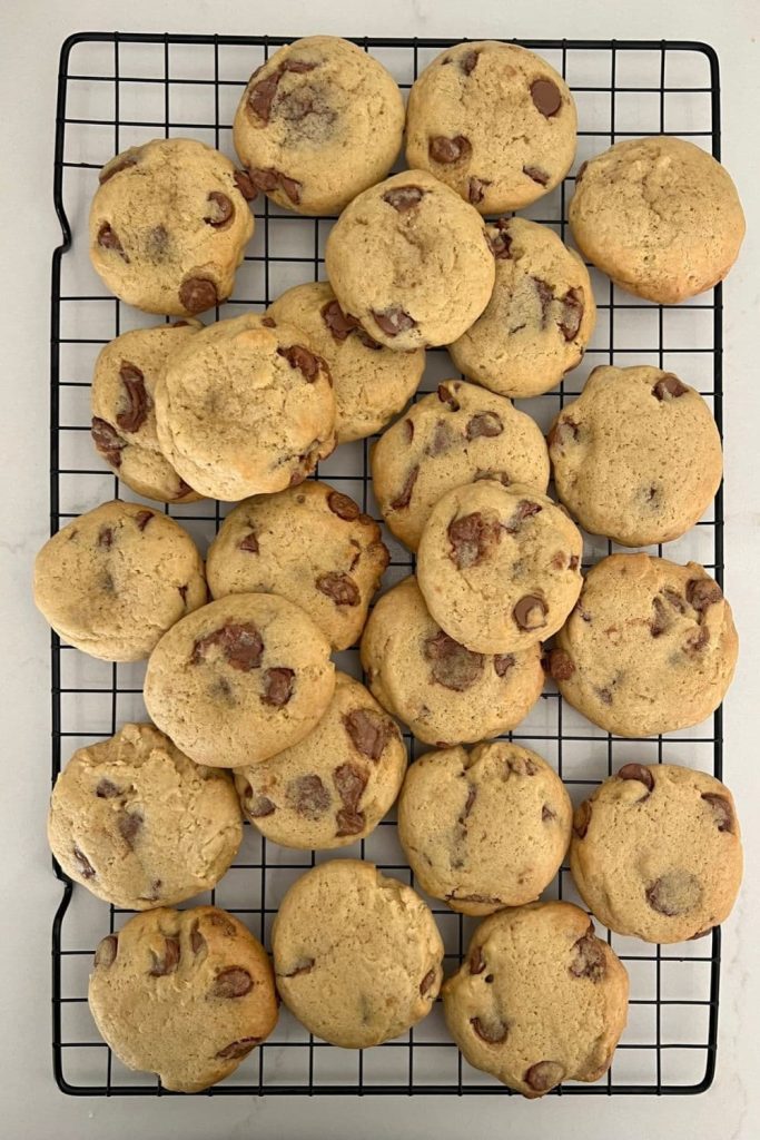 A stack of sourdough chocolate chip cookies on a black cooling rack.