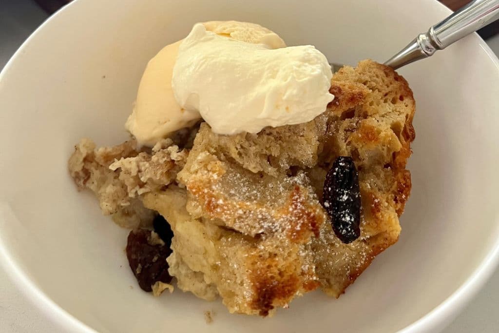 A bowl of sourdough comfort food! A bowl of sourdough bread pudding topped with whipped cream and ice cream.