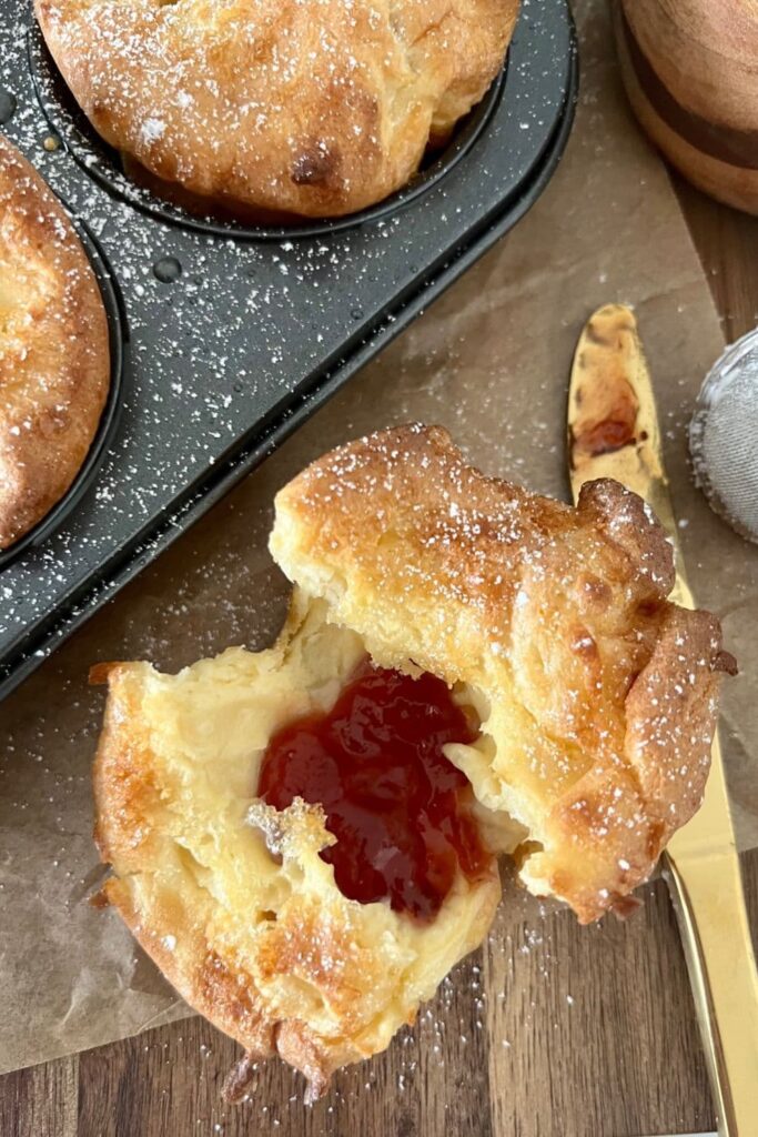 Sourdough popover that has been broken open and spread with jam.